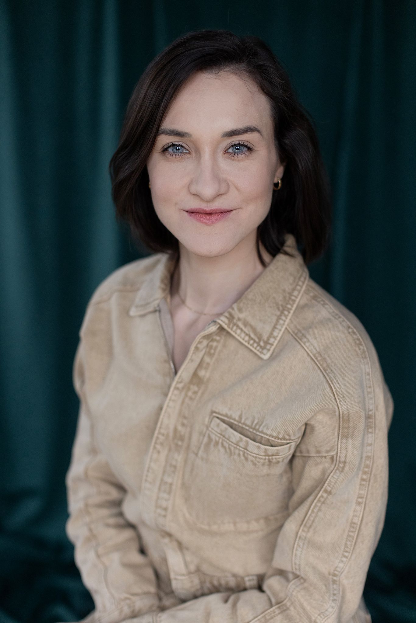 Magdalena Tarnawska-Stus - uśmiechnięty headshot, dłoń przy brodzie, jasna sukienka