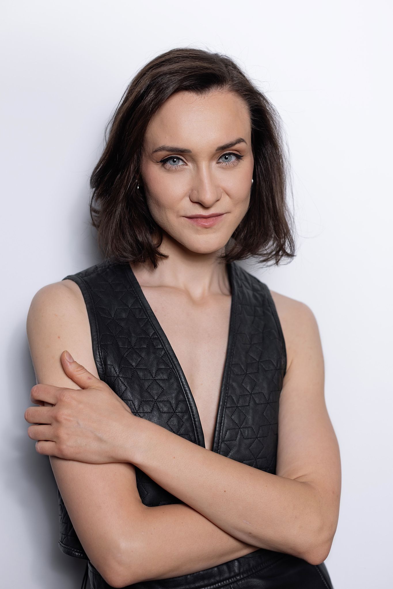 Magdalena Tarnawska-Stus - portret w beżowym kombinezonie, zielona kurtyna w tle